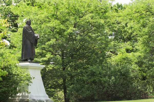 Statue of Martin Luther nestled in the trees on Luther College Campus