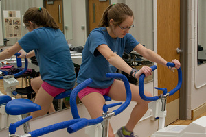 A student peddling a workout bike in a Physiology of Exercise Lab.