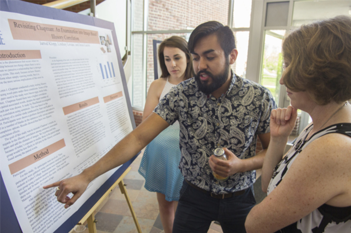 Psychology students present their work to a professor.