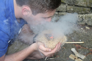 Max Rooney (’17) coaxes an ember into flame that he created using a fire-making kit he constructed as part of the Experimental Archaeology course.