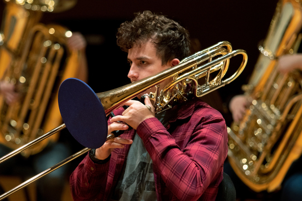 A photo of a student holding a trombone with a bell cover.