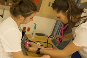 Nursing students practice taking a patient's blood pressure.