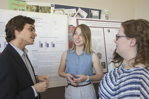 Students discussing their physics poster at the student research symposium.
